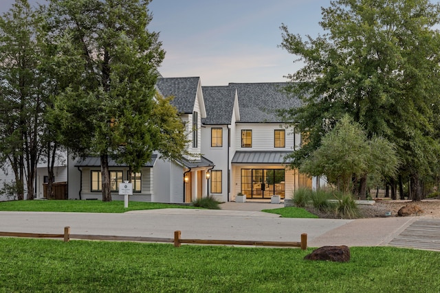 view of front facade featuring a standing seam roof, metal roof, a front yard, and roof with shingles