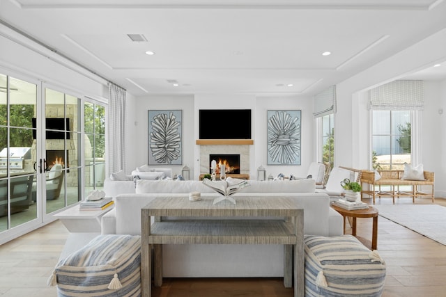 living area featuring light wood-style flooring, recessed lighting, visible vents, and a warm lit fireplace