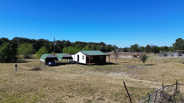 view of yard with a rural view, a detached carport, an outdoor structure, and fence