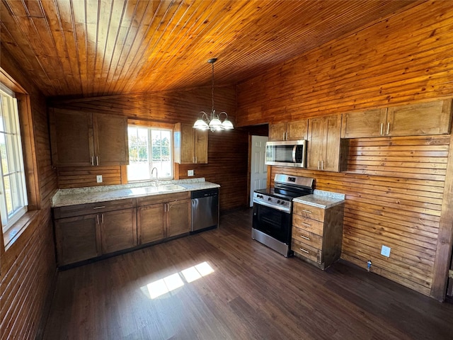 kitchen with dark wood-type flooring, a sink, appliances with stainless steel finishes, light countertops, and vaulted ceiling