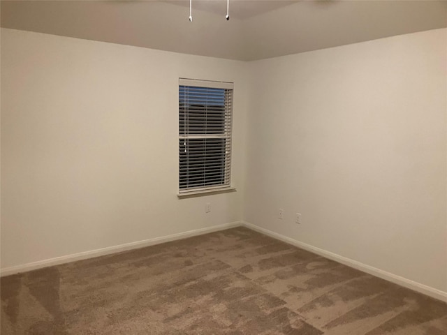 unfurnished room featuring carpet flooring, baseboards, and vaulted ceiling