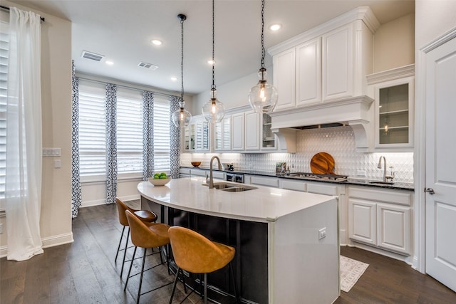 kitchen featuring a kitchen island with sink, visible vents, dark wood-style flooring, and a sink