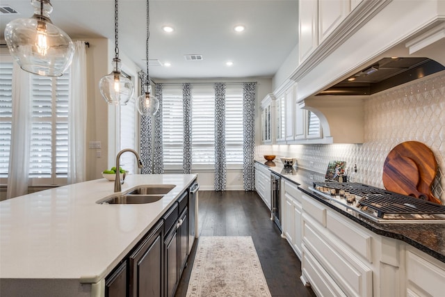 kitchen with tasteful backsplash, visible vents, premium range hood, dark wood finished floors, and a sink