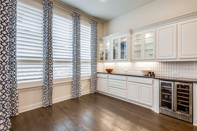 interior space with baseboards, wine cooler, dark wood finished floors, a dry bar, and decorative backsplash