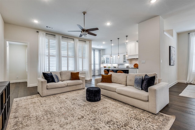 living room with dark wood finished floors, visible vents, recessed lighting, and baseboards