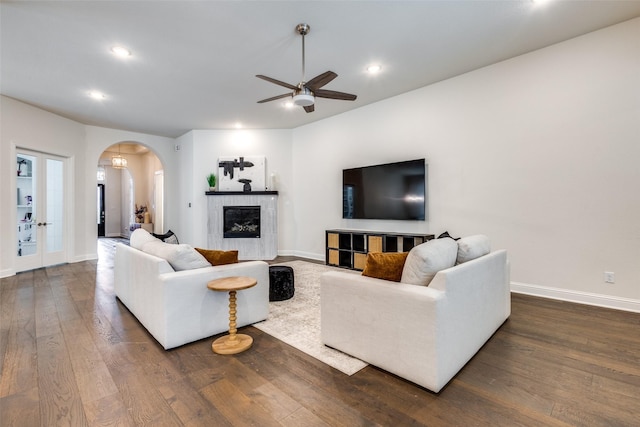 living room featuring arched walkways, dark wood-style floors, recessed lighting, and baseboards