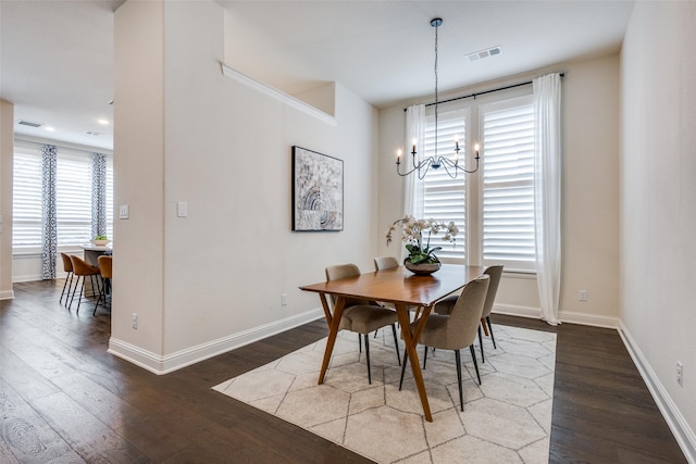 dining space featuring a notable chandelier, visible vents, baseboards, and wood finished floors