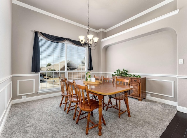 dining room featuring a wainscoted wall, carpet floors, ornamental molding, an inviting chandelier, and a decorative wall