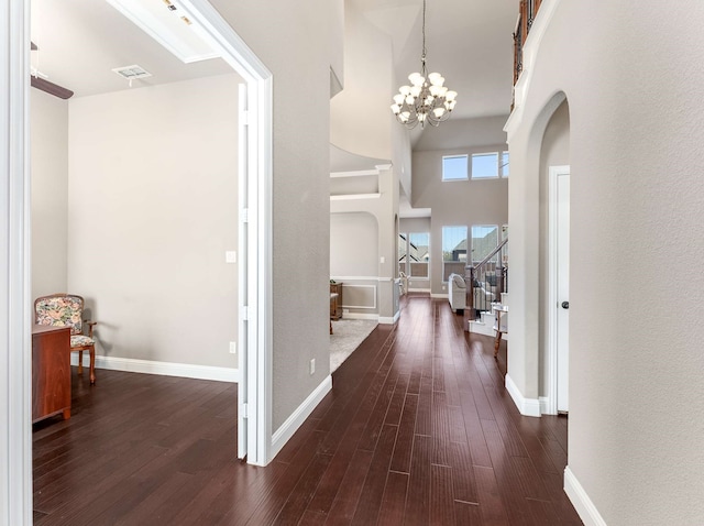 hallway featuring dark wood finished floors, visible vents, stairway, and baseboards