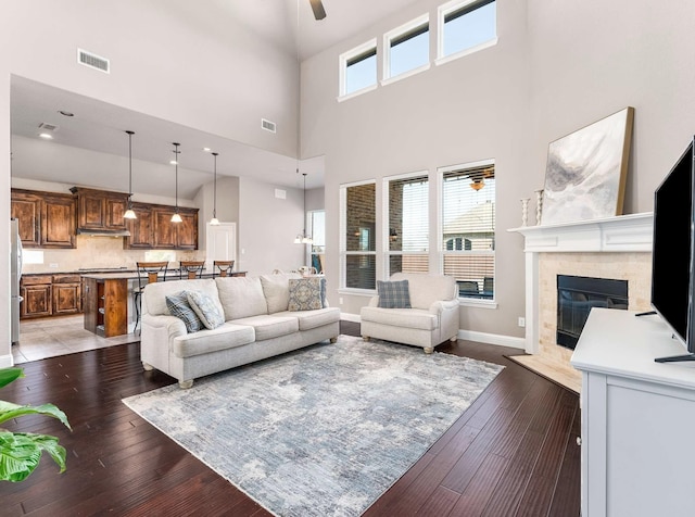 living area featuring visible vents, wood-type flooring, baseboards, and a fireplace with flush hearth