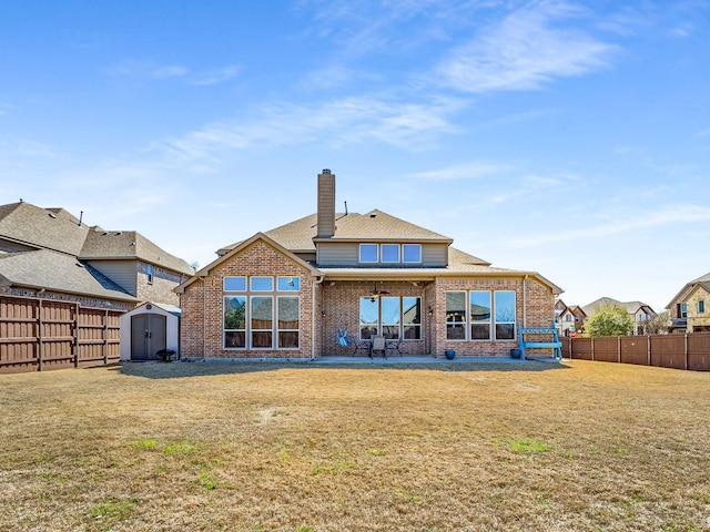 back of property featuring brick siding, a fenced backyard, a yard, an outbuilding, and a storage unit