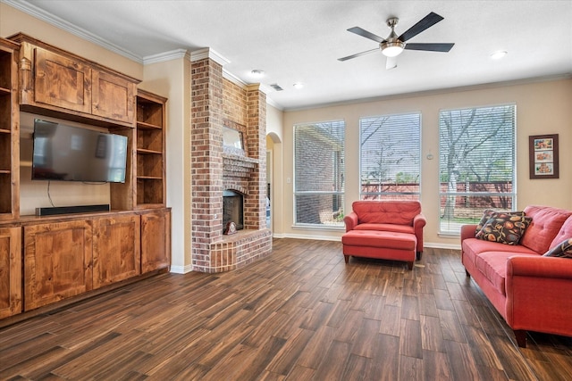 living area with a ceiling fan, baseboards, dark wood-style flooring, crown molding, and a brick fireplace