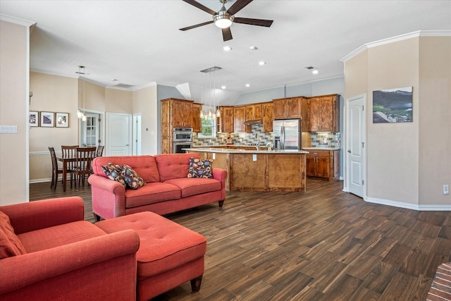 living area with baseboards, dark wood finished floors, crown molding, and ceiling fan with notable chandelier