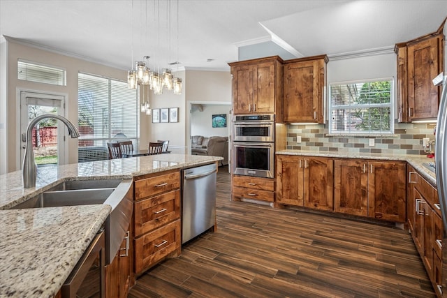 kitchen featuring dark wood finished floors, a sink, stainless steel appliances, crown molding, and backsplash