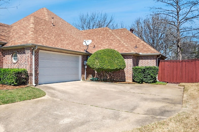 view of front of house featuring fence, roof with shingles, an attached garage, concrete driveway, and brick siding