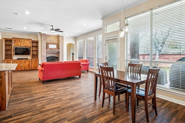 dining area featuring a ceiling fan, a healthy amount of sunlight, dark wood-style flooring, and crown molding