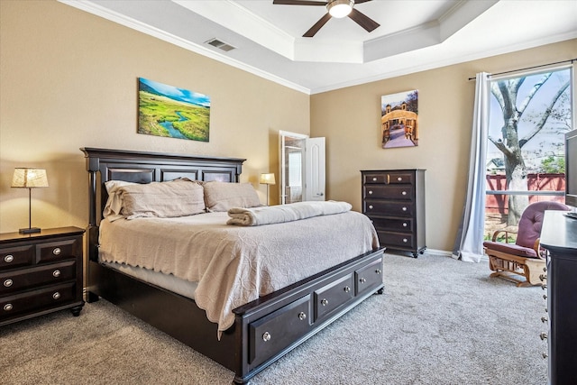 bedroom featuring visible vents, a tray ceiling, ceiling fan, crown molding, and light colored carpet