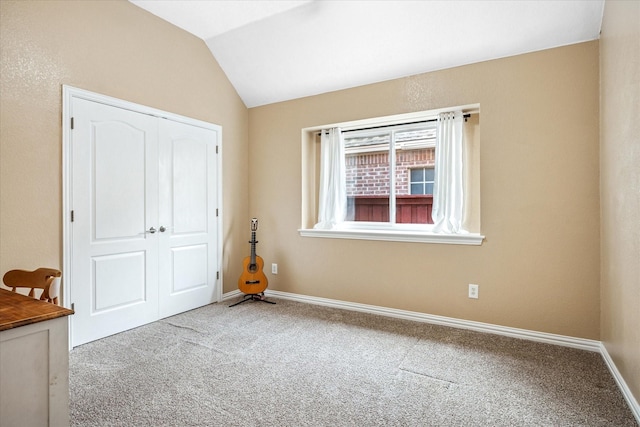 unfurnished bedroom with vaulted ceiling, carpet, a closet, and baseboards