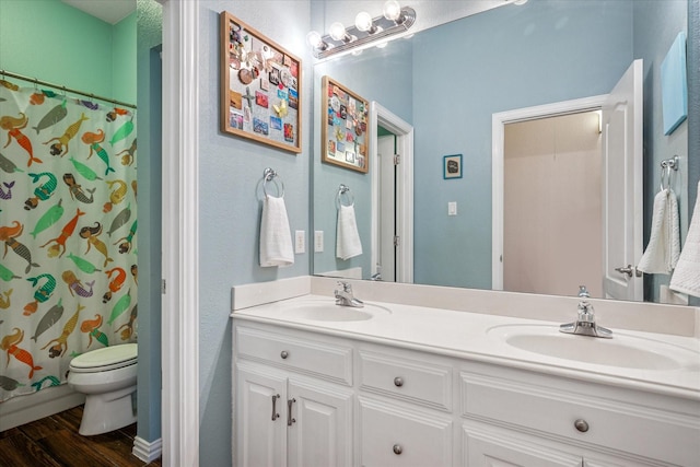 full bath featuring double vanity, wood finished floors, and a sink