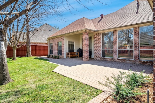 back of property with brick siding, a patio area, a lawn, and fence