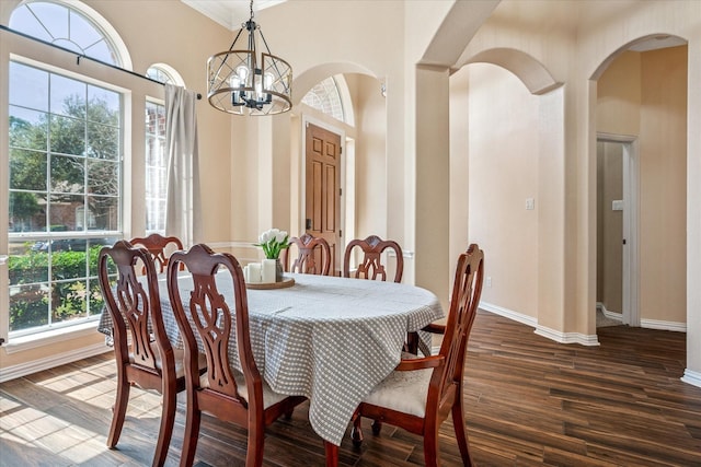 dining area featuring arched walkways, dark wood finished floors, baseboards, and an inviting chandelier