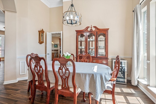 dining space with a notable chandelier, wood finished floors, a towering ceiling, and ornamental molding