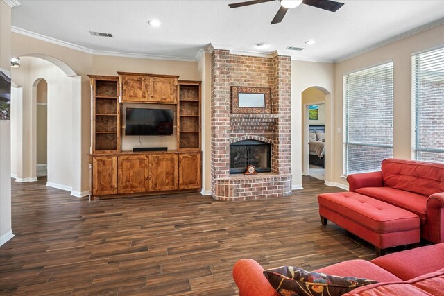 living area with a fireplace, crown molding, dark wood-style floors, and visible vents