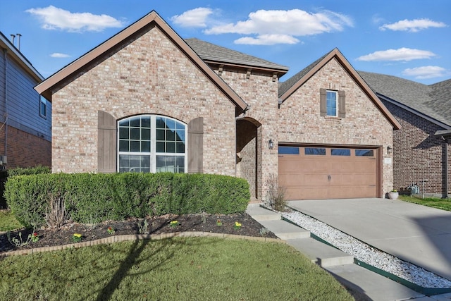 view of front of home with a garage, brick siding, driveway, and roof with shingles