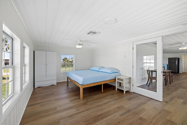 bedroom with visible vents, crown molding, light wood-style flooring, freestanding refrigerator, and a ceiling fan