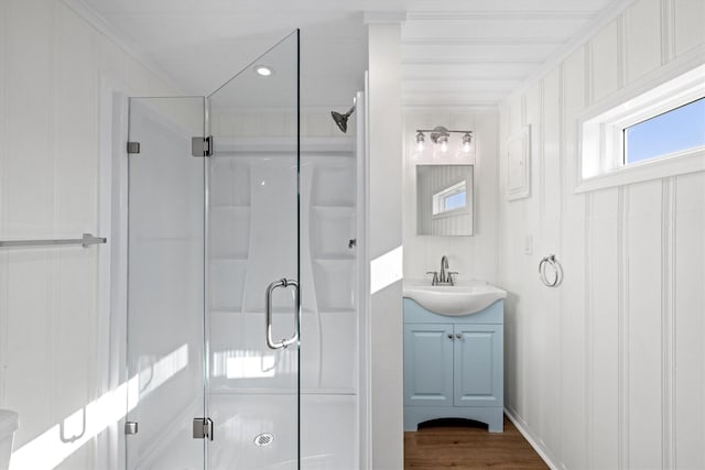 full bathroom with vanity, wood finished floors, a stall shower, and ornamental molding