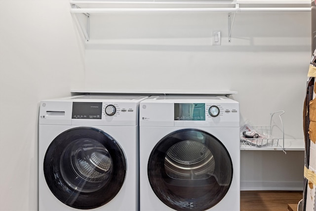 laundry room featuring washer and dryer, baseboards, wood finished floors, and laundry area