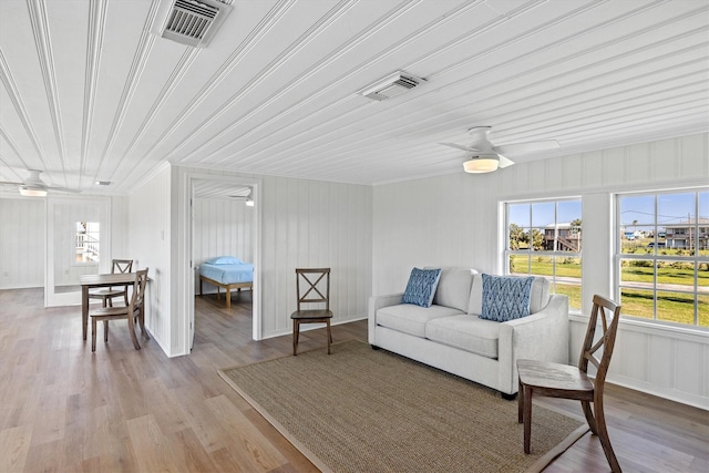 living room with wood finished floors, a ceiling fan, visible vents, and a healthy amount of sunlight