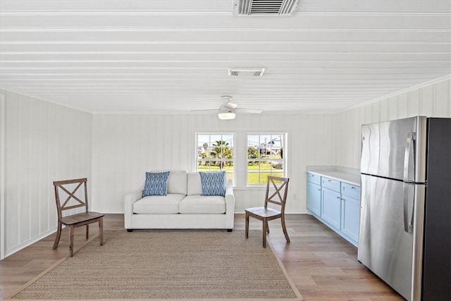 sitting room featuring visible vents, ceiling fan, crown molding, and light wood finished floors