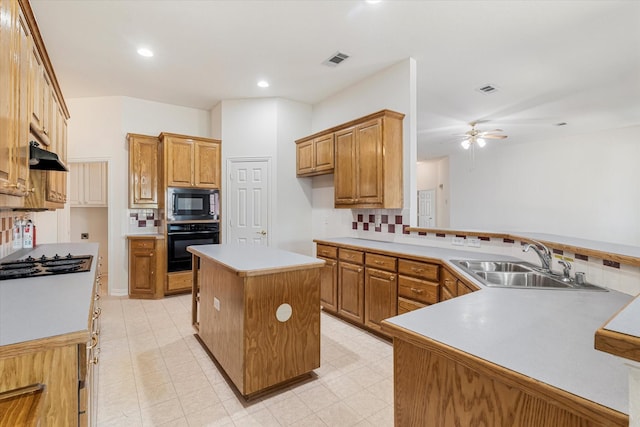 kitchen featuring brown cabinetry, a sink, black appliances, tasteful backsplash, and a center island