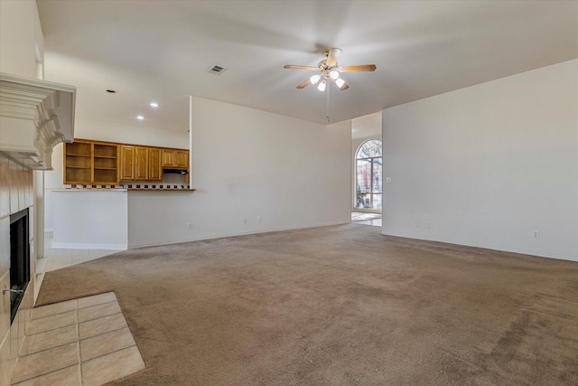 unfurnished living room featuring a ceiling fan, baseboards, visible vents, light carpet, and a tiled fireplace