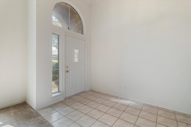 foyer entrance featuring light tile patterned floors, baseboards, and a towering ceiling