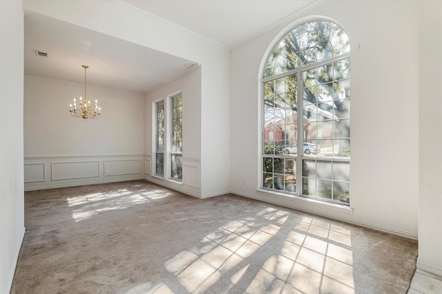 unfurnished dining area with a decorative wall, ornamental molding, an inviting chandelier, and carpet floors