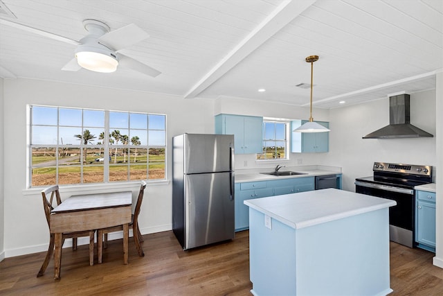 kitchen with blue cabinetry, wall chimney range hood, light countertops, stainless steel appliances, and a sink