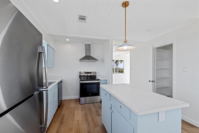 kitchen featuring visible vents, appliances with stainless steel finishes, wall chimney exhaust hood, and blue cabinets