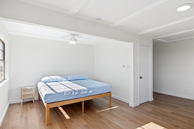 bedroom with beam ceiling, ceiling fan, light wood finished floors, and baseboards