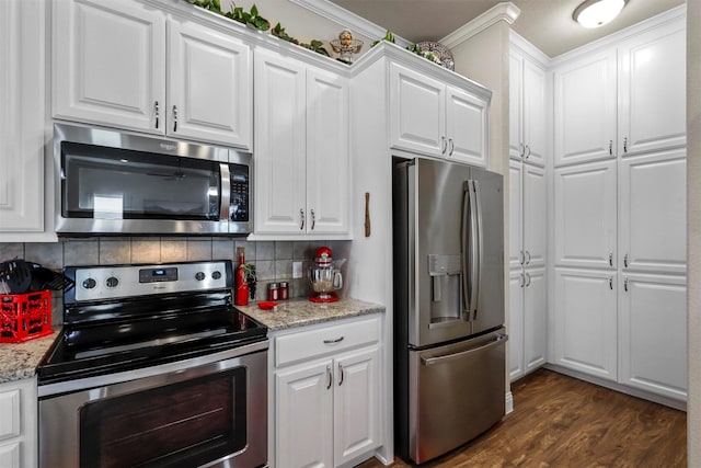 kitchen featuring light stone counters, dark wood finished floors, appliances with stainless steel finishes, white cabinetry, and backsplash