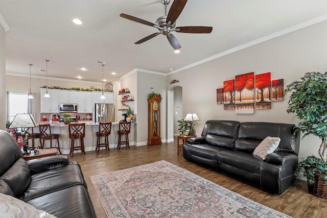 living room with arched walkways, wood finished floors, a ceiling fan, and crown molding