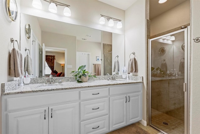 bathroom with double vanity, a shower stall, and a sink