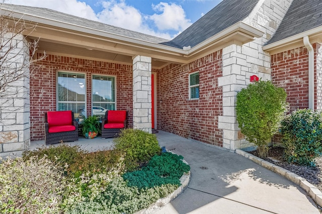 doorway to property featuring brick siding and a shingled roof