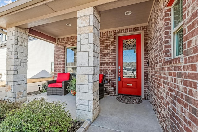 property entrance with brick siding and a porch