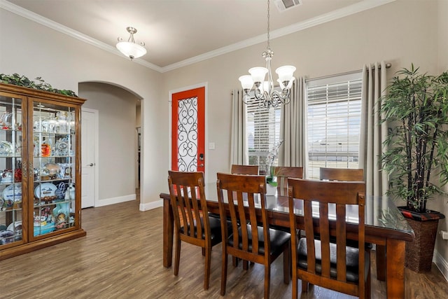 dining room with crown molding, wood finished floors, arched walkways, and baseboards