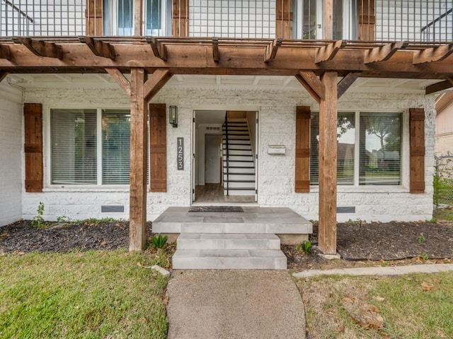 view of exterior entry featuring crawl space and a balcony