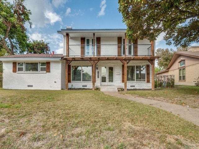 view of front of property featuring crawl space, brick siding, a balcony, and a front lawn