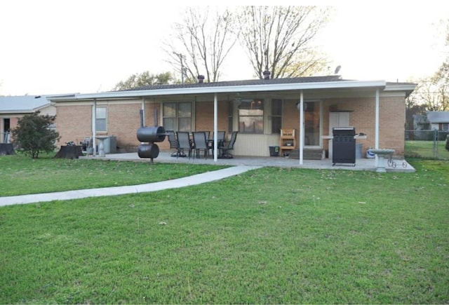 rear view of property featuring brick siding, a patio, and a yard