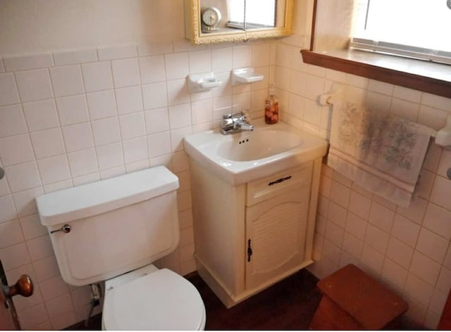 bathroom featuring toilet, tile walls, and vanity